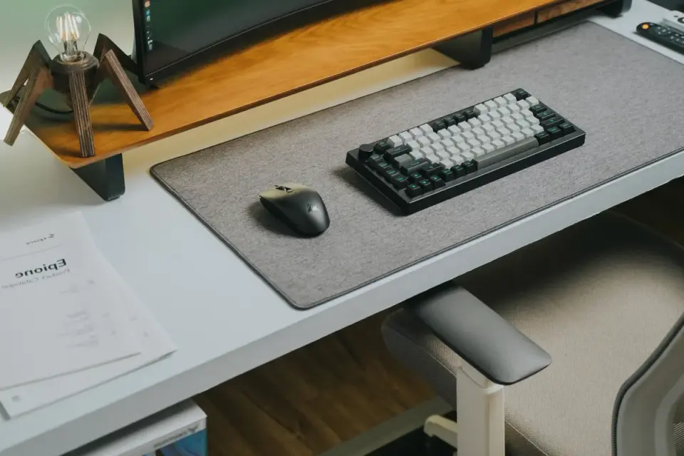 A dog resting calmly on a mat with a chew toy a few feet from a home office desk