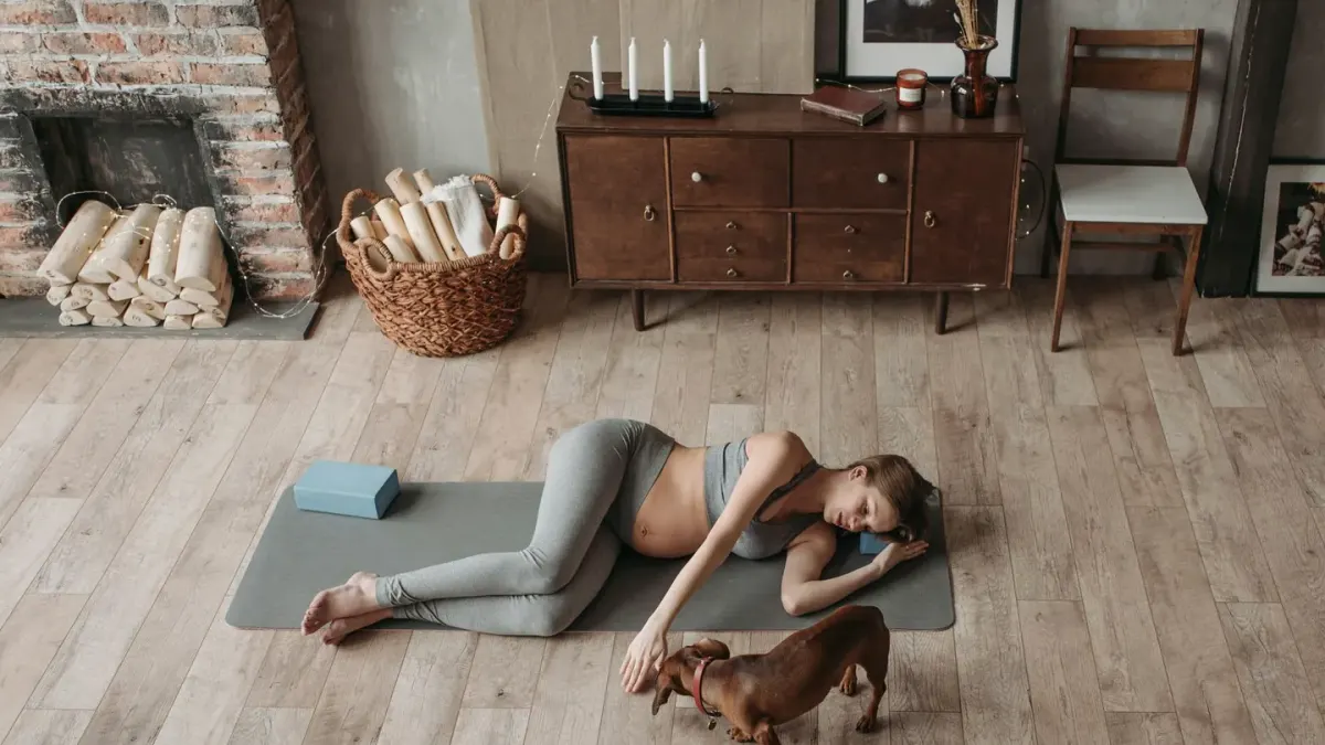 A dog resting on a bed while its owner is visible walking away in the background