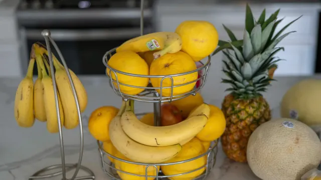 A dog sniffing a peeled banana resting on a kitchen counter