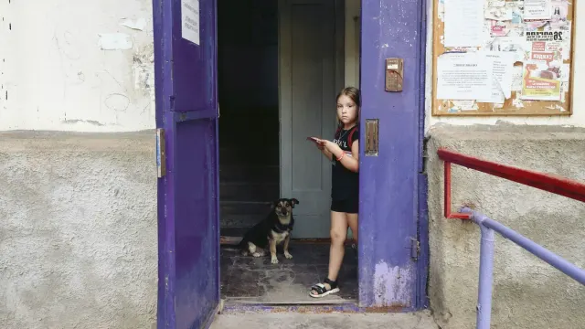 A dog standing alert near a front door while an owner holds a leash