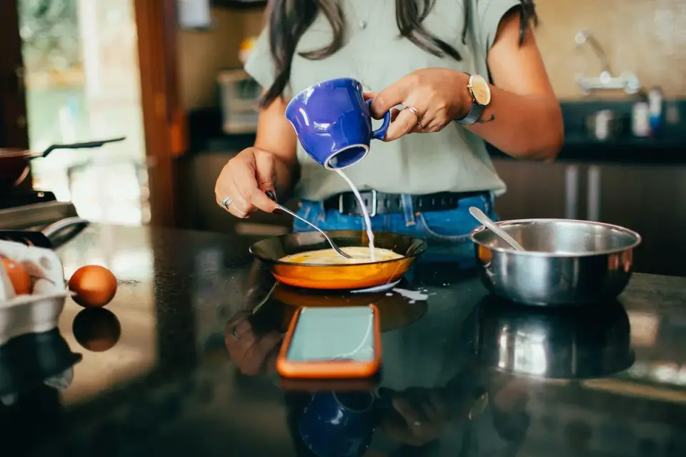 A golden retriever sitting near the stove while eggs cook in a pan