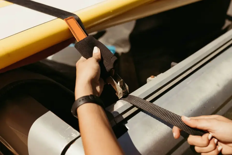 A hard-sided dog travel crate anchored in a car&#x27;s cargo area with tie-down straps