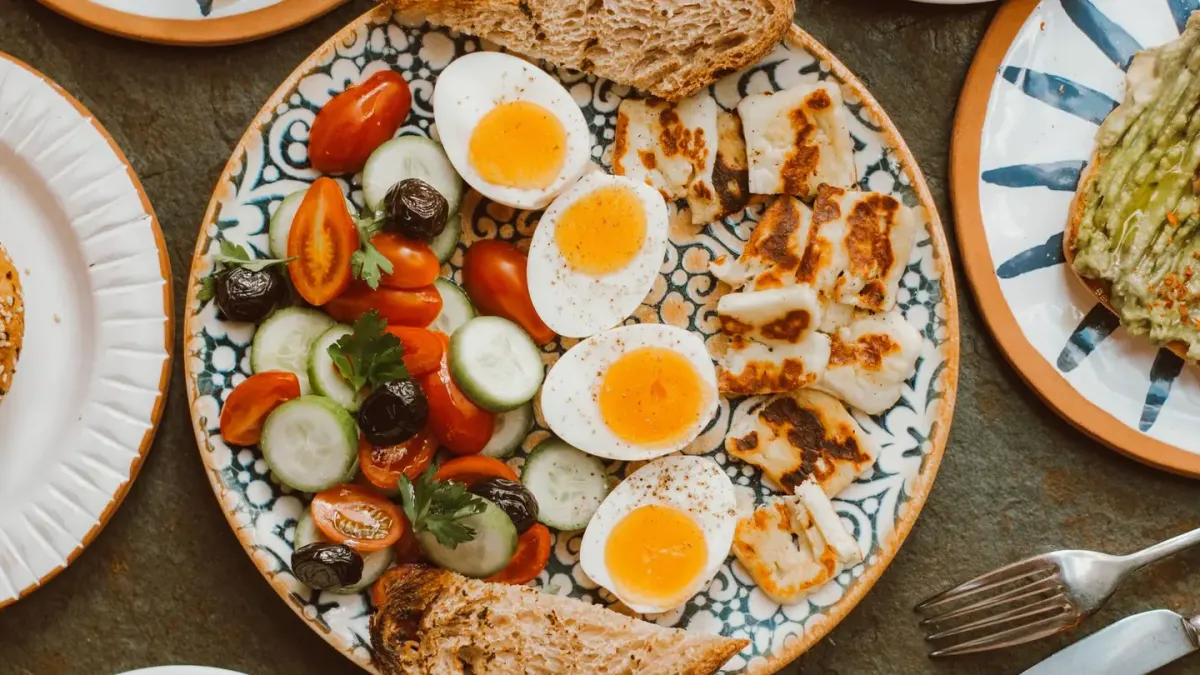 A sliced hard-boiled egg next to two whole raw eggs on a kitchen counter