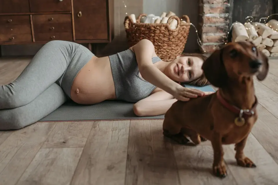 A trainer delivering a treat to a dog lying calmly on a place mat