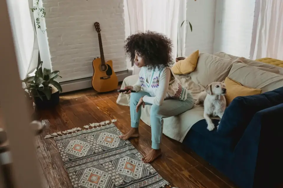 An owner sitting quietly on the floor while a dog cautiously sniffs the edges of a new apartment