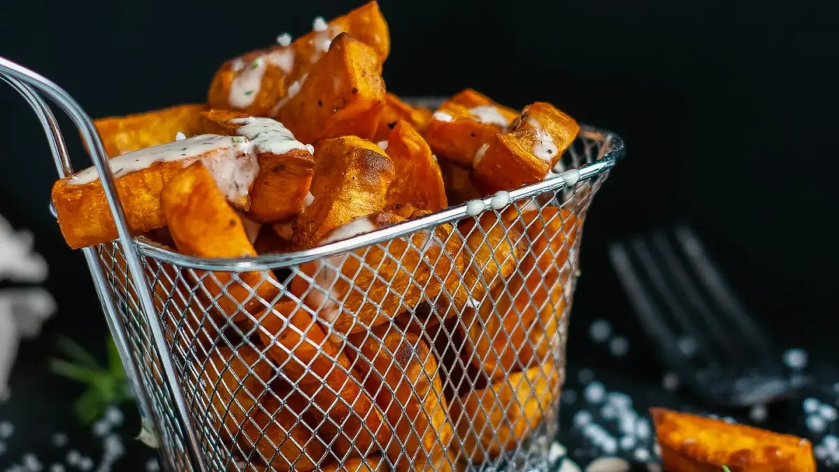 Cubed cooked sweet potato in a stainless steel dog bowl