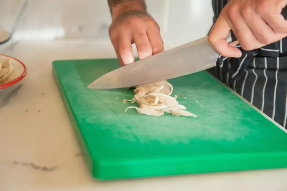 Sliced white button mushrooms on a wooden cutting board