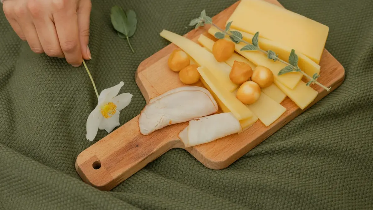 Slices of ham on a wooden cutting board with a dog watching from the kitchen floor